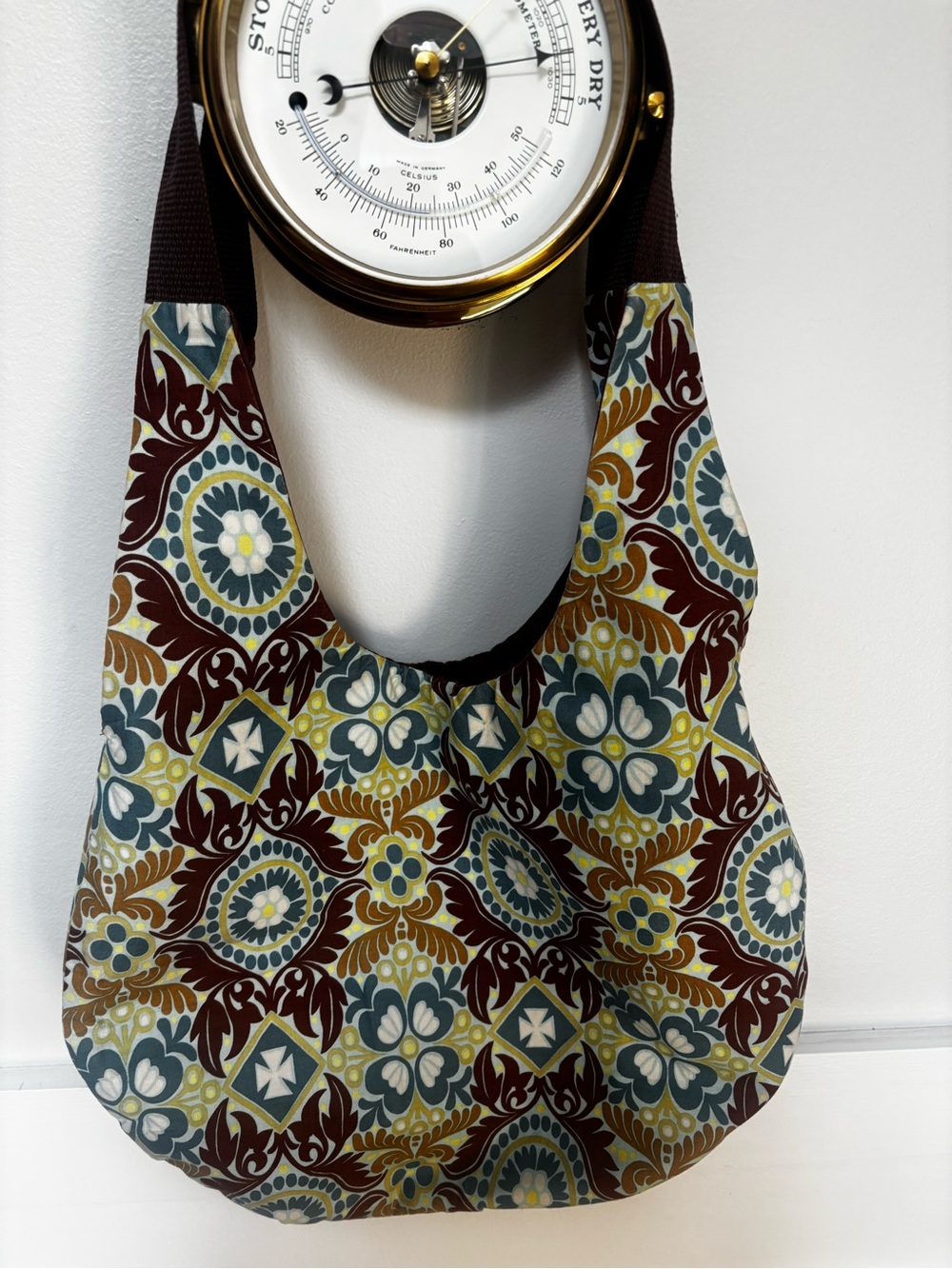 slouchy hobo shoulder bag features a curved strap and an intricate blue, brown,